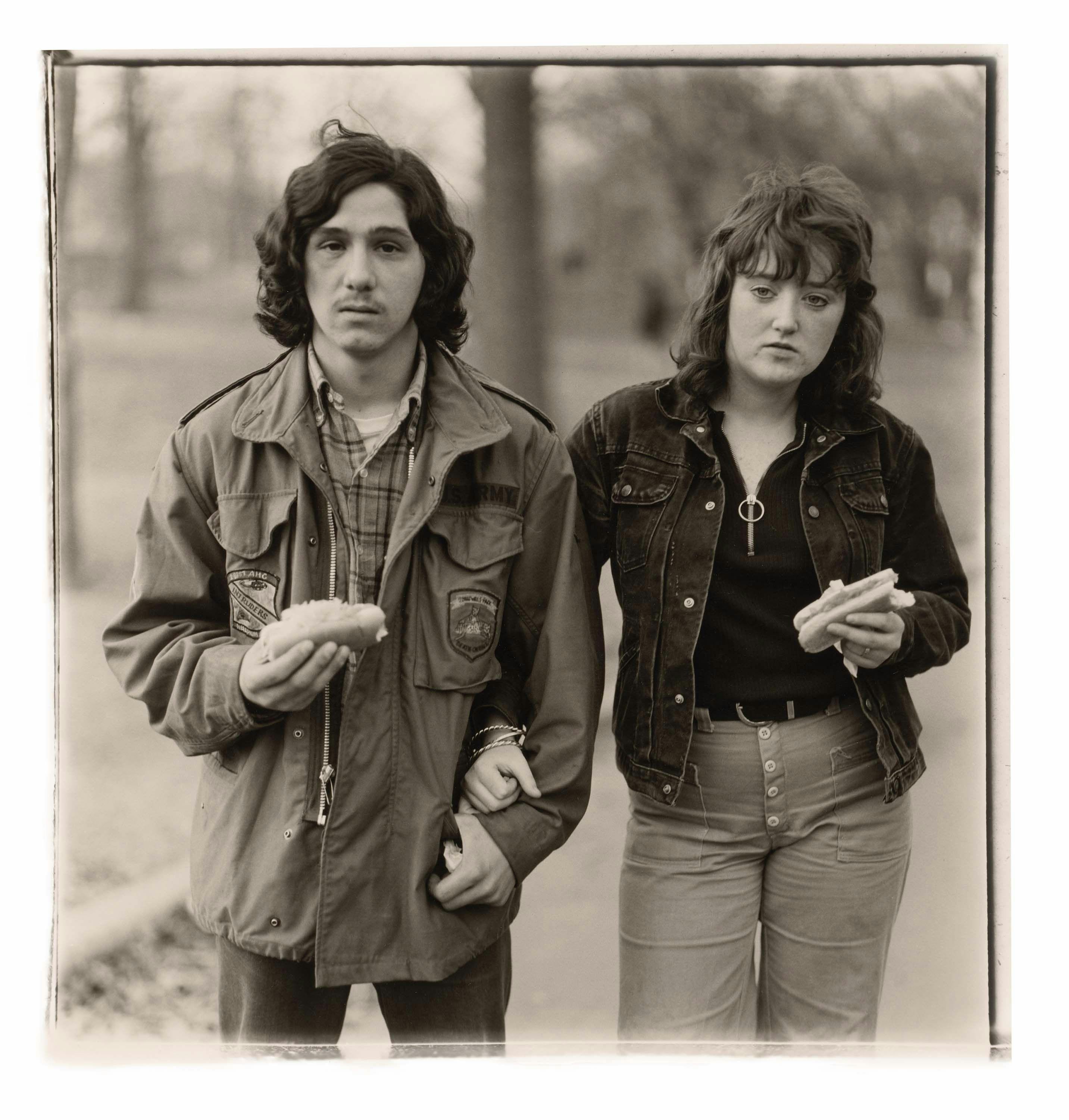 A gelatin silver print by Diane Arbus, titled A young man and his girlfriend with hot dogs in the park, N.Y.C. 1971, dated 1971.