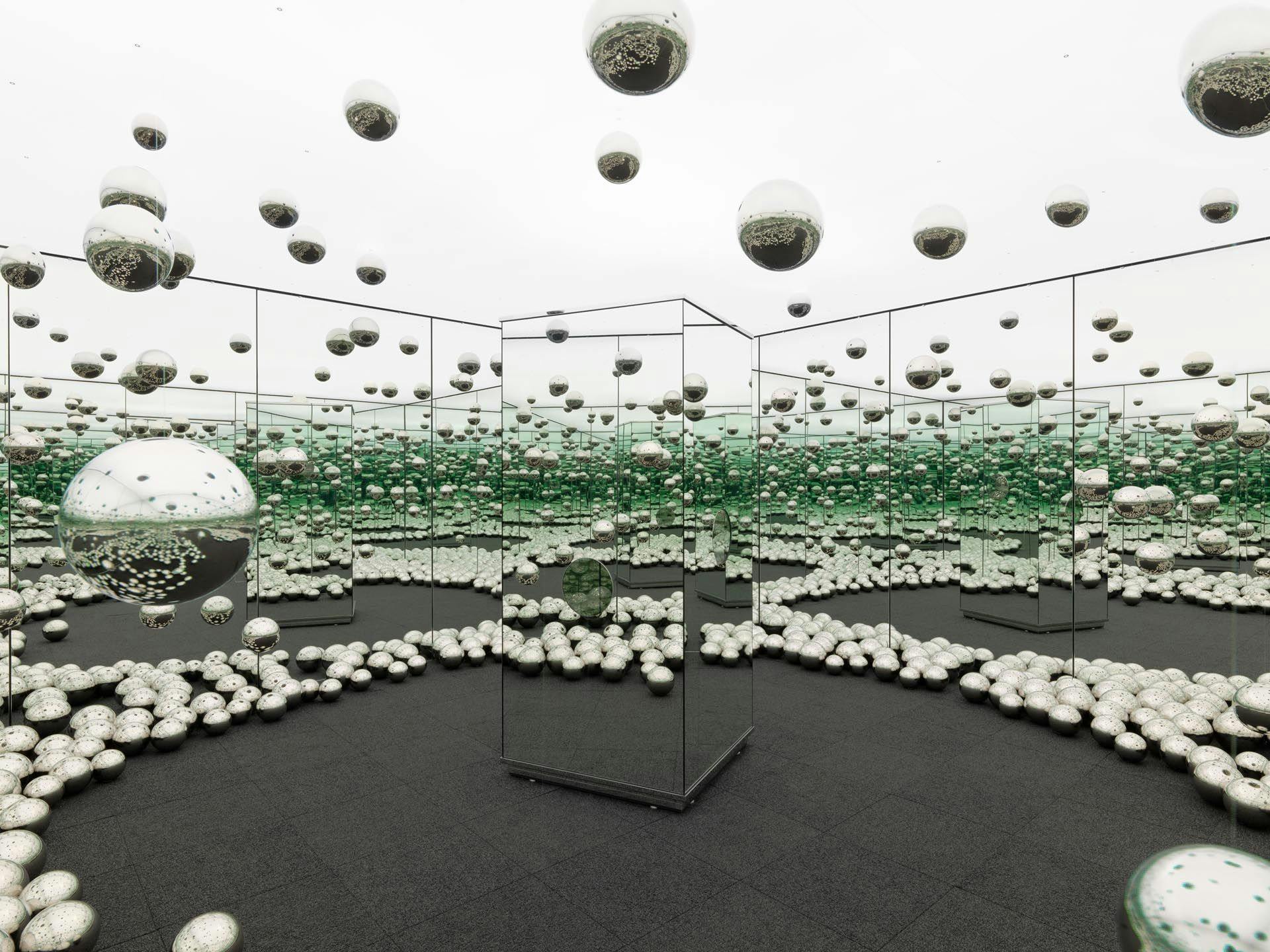 An experiential installation by Yayoi Kusama, comprised of mirrors, wood, LED lighting system, metal, steel balls, and carpeting, titled Infinity Mirrored Room - Let's Survive Forever, dated 2017.