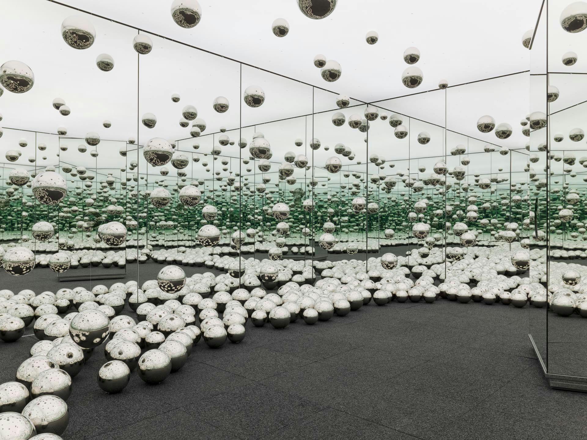 A view of an experiential installation by Yayoi Kusama, comprised of mirrors, wood, LED lighting system, metal, steel balls, and carpeting, titled Infinity Mirrored Room - Let's Survive Forever, dated 2017.