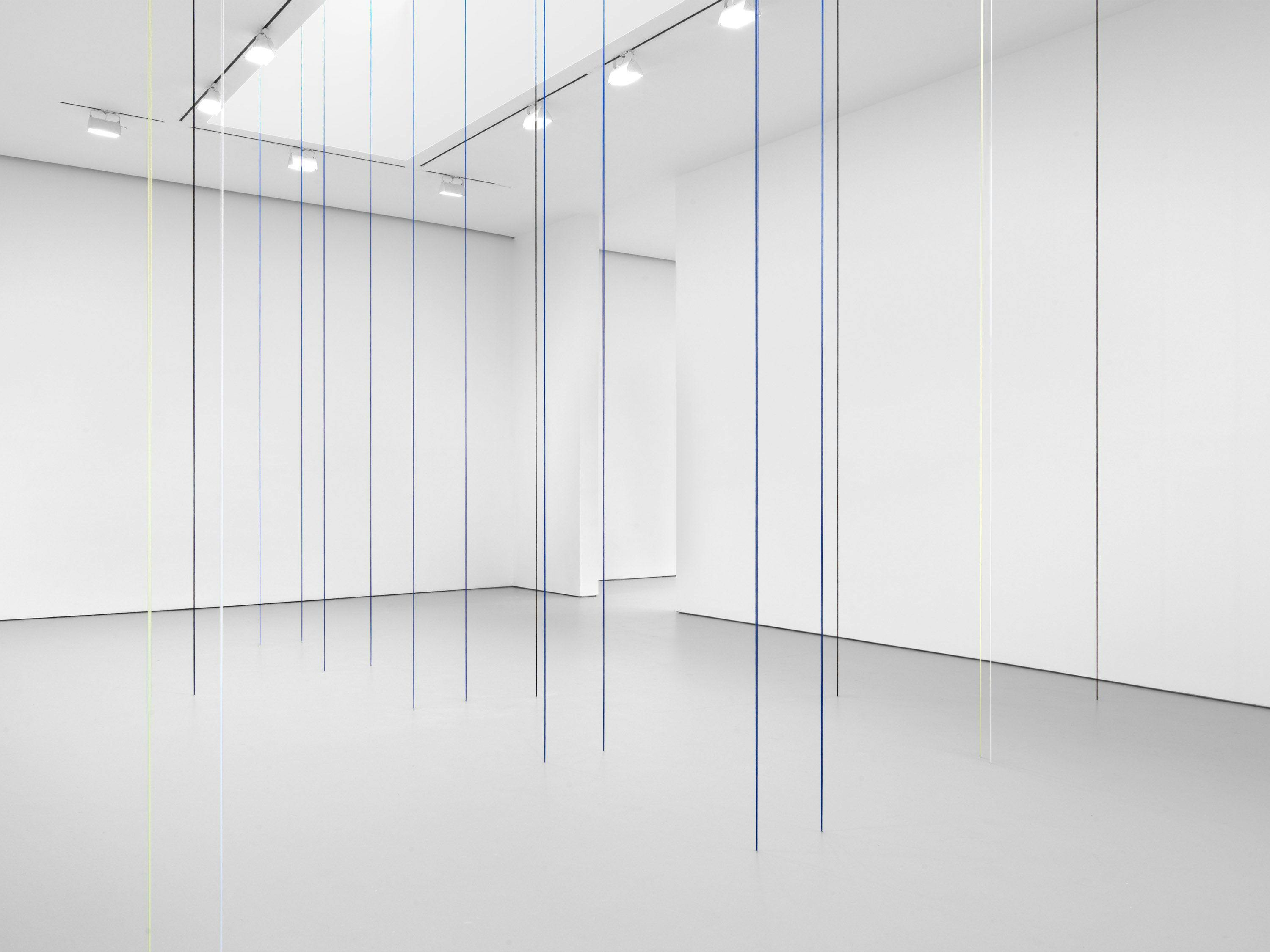 A black, blue, white, and light yellow acrylic yarn artwork by Fred Sandback, titled Untitled (Sculptural Study, Eighteen-part Architectonic Vertical Construction), 1987 and 2018.