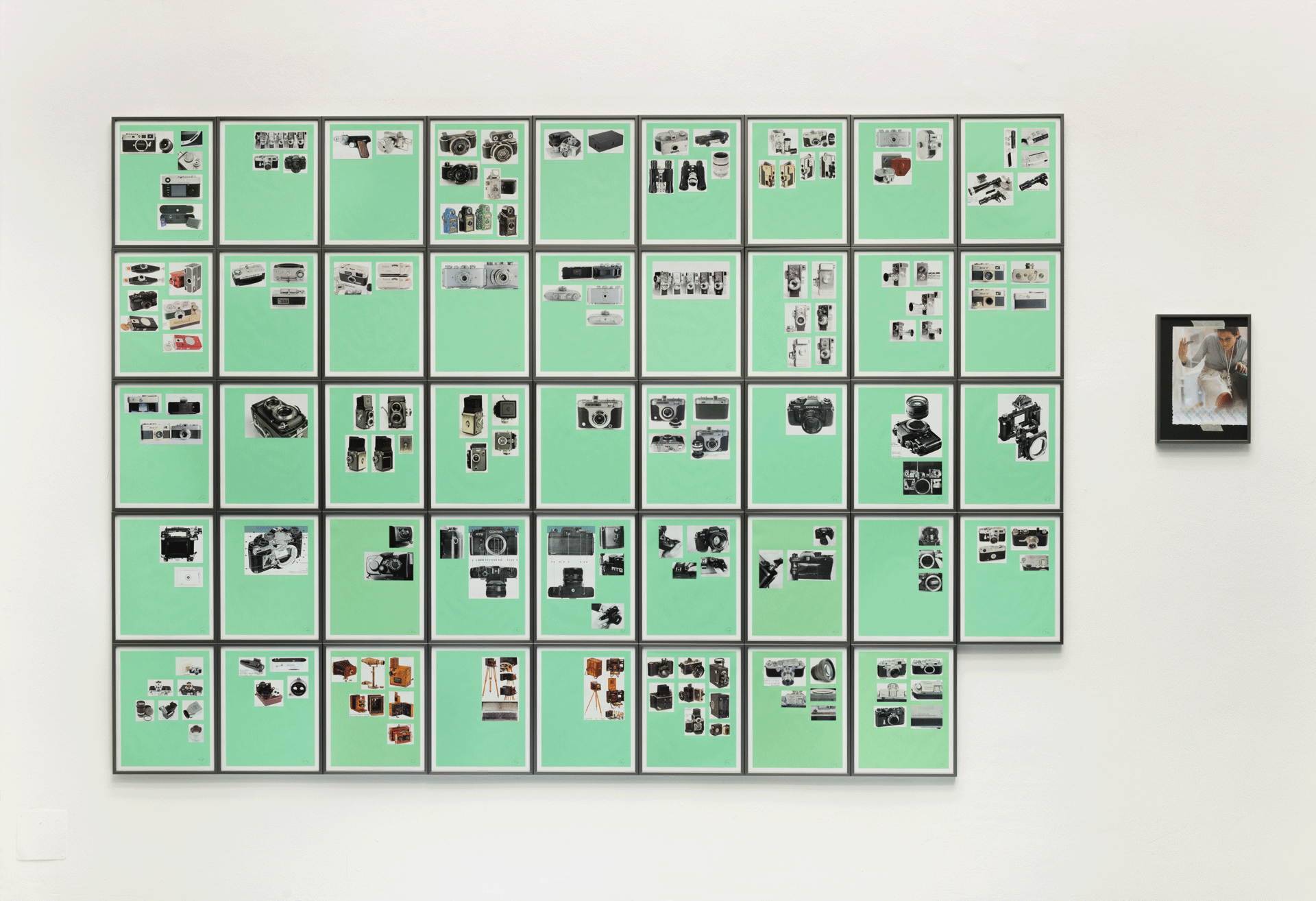 An installation of 45 mixed media collaged prints of camera cutouts on green paper, titled Supplement '14 (Mixed Typologies) #6, dated 2014.