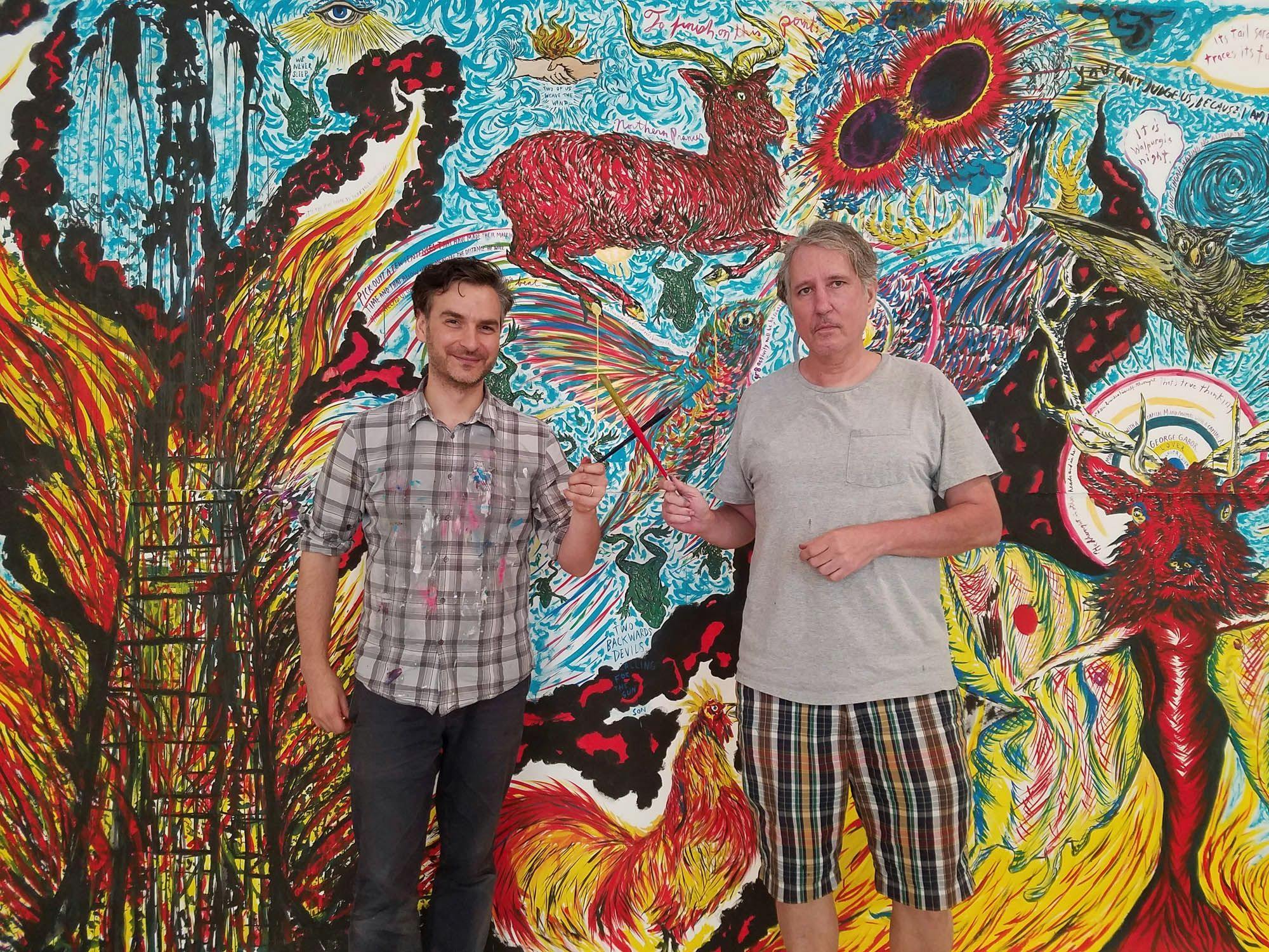 A photograph of Marcel Dzama and Raymond Pettibon working on their collaborative mural, dated 2016.